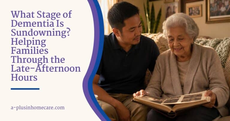 A caregiver and an older woman look through a photo album together on a sofa in warm late-afternoon light.